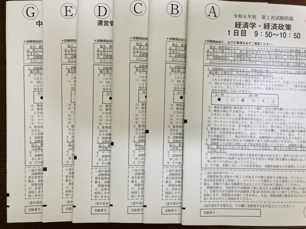 筆者がテストを受けた、2024年中小企業診断士一次試験の問題冊子が6冊分載っている写真。